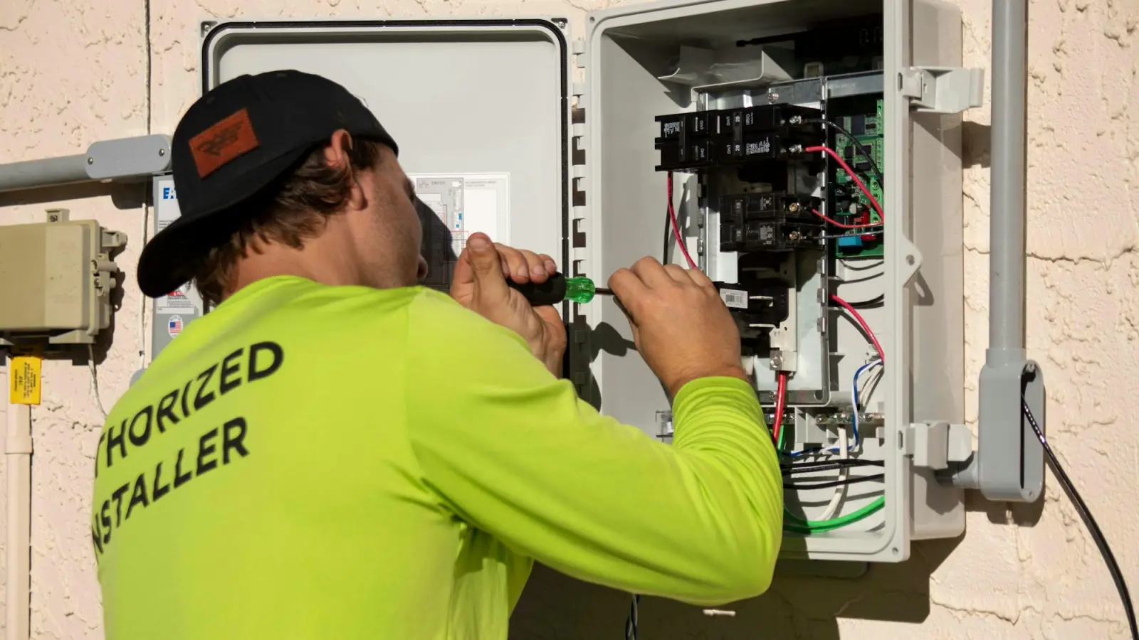 An electrician working inside an open electrical panel