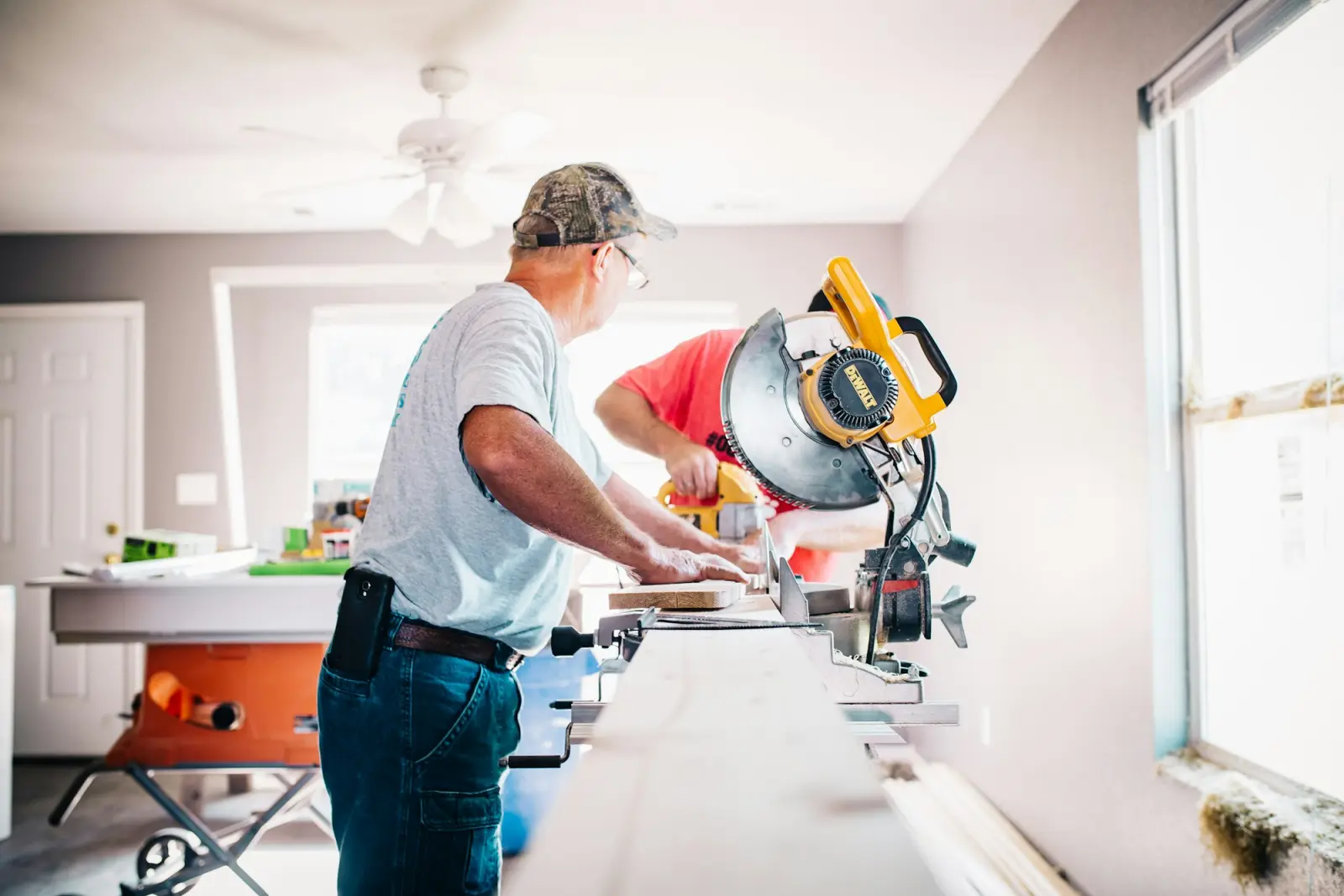 A handyman cutting trim with a miter saw inside a home