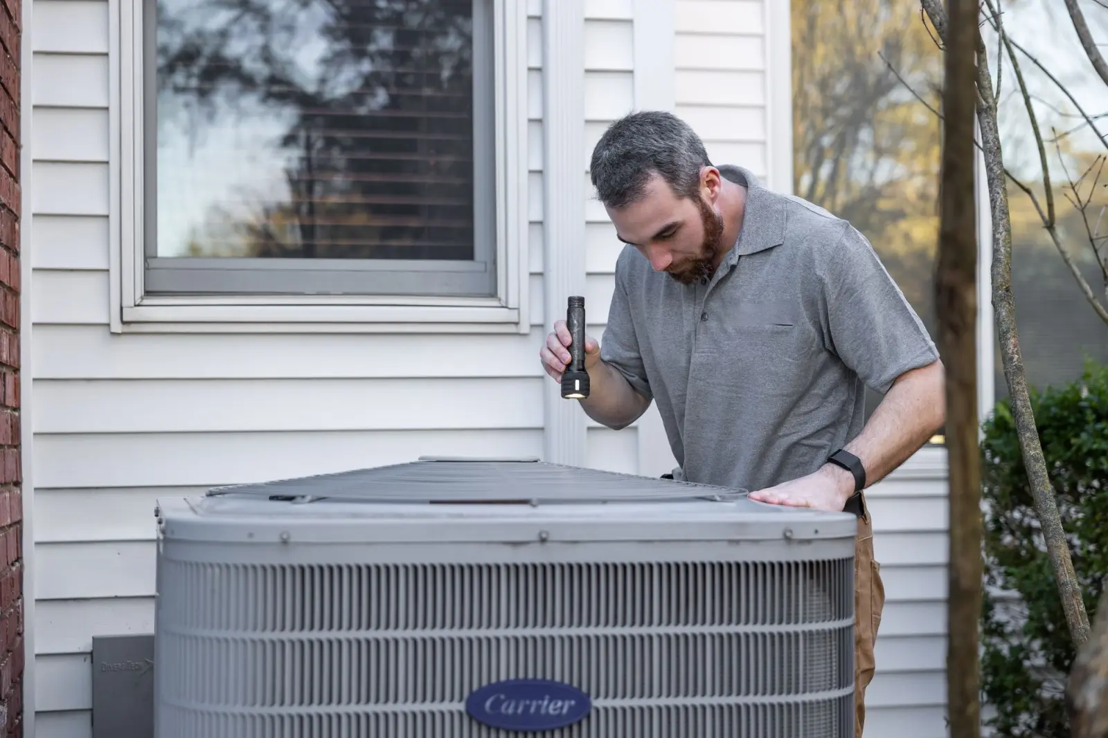 An HVAC technician servicing an outdoor air conditioning condenser