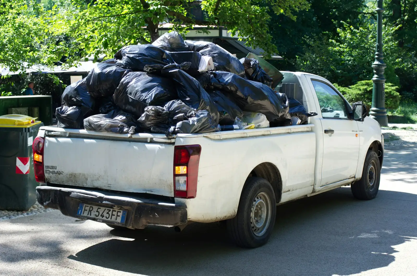 A white pickup truck loaded with black garbage bags
