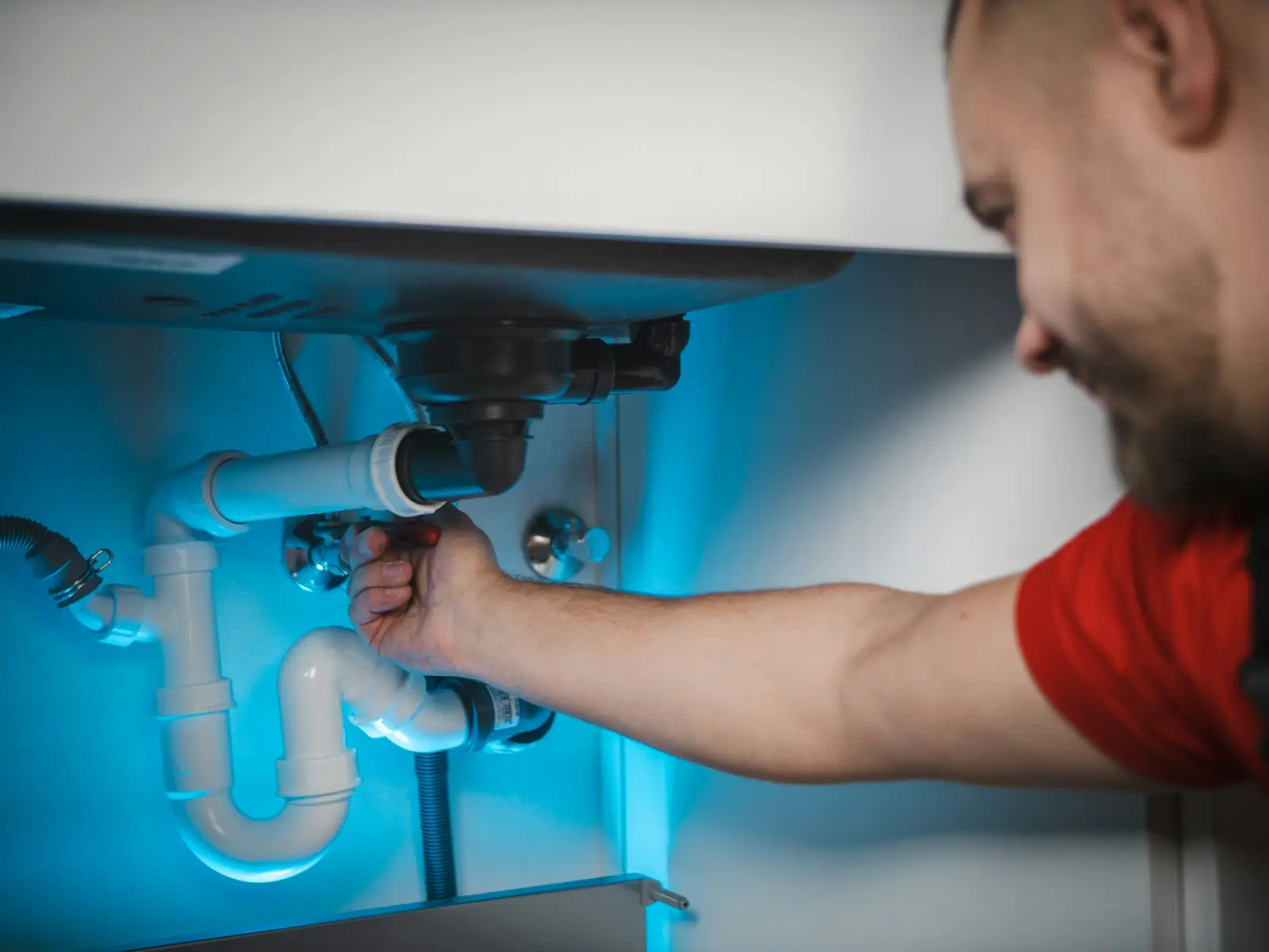 A plumber repairing pipes under a sink